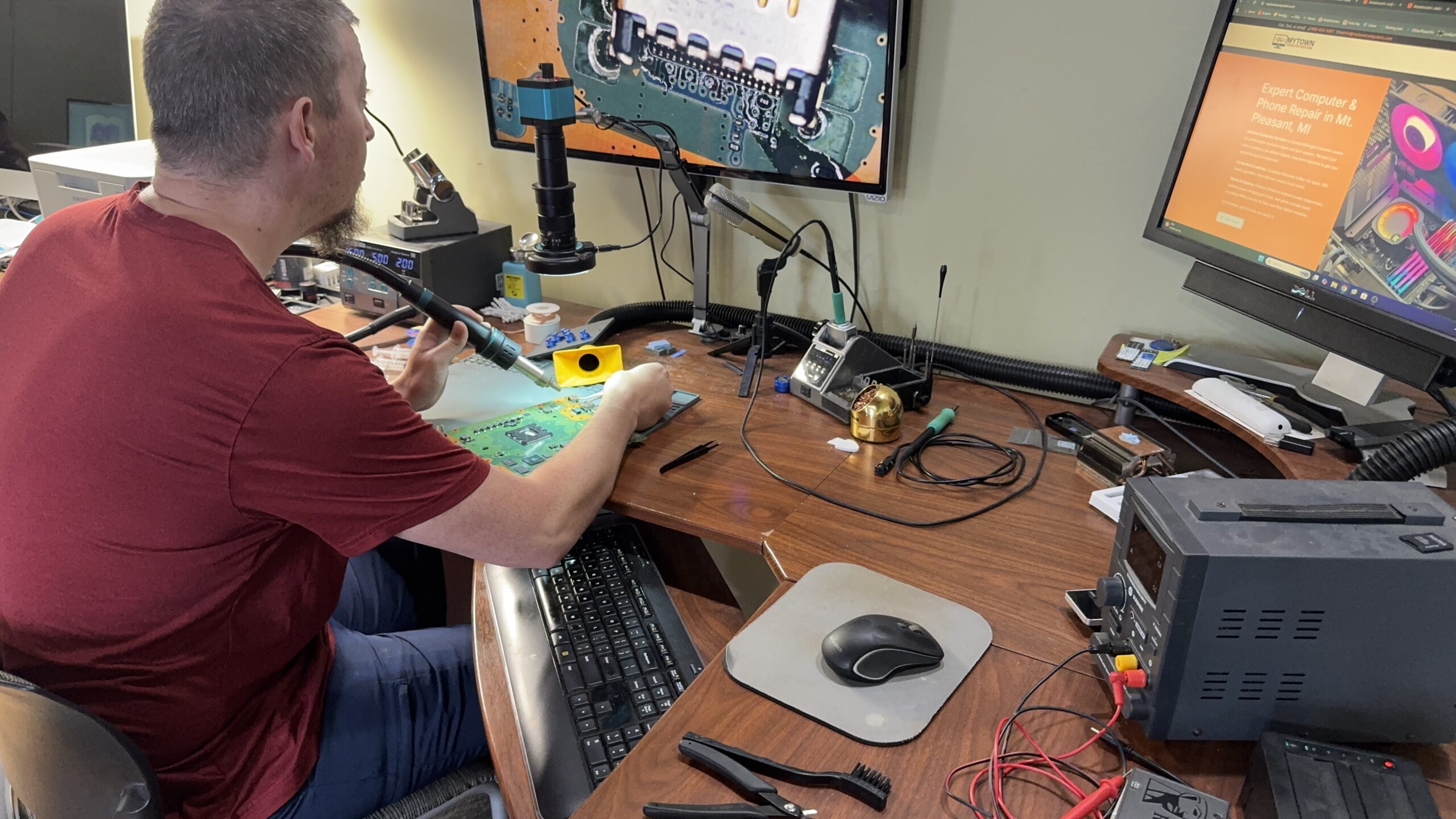 Technician performing micro-soldering HDMI port replacement on a gaming console circuit board at MyTown Computer Service in Mt. Pleasant MI.