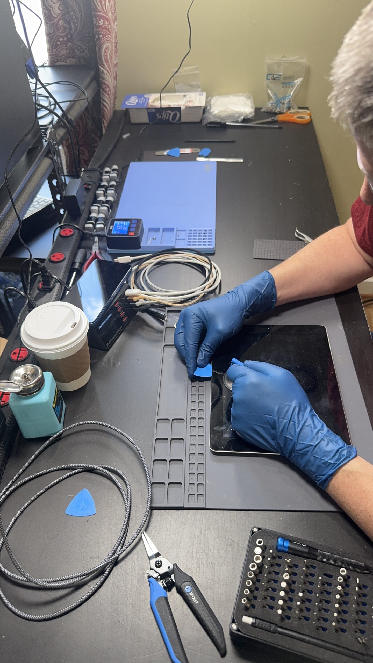 Technician replacing a tablet screen using precision tools and heat pad at MyTown Computer Service in Mt. Pleasant MI.